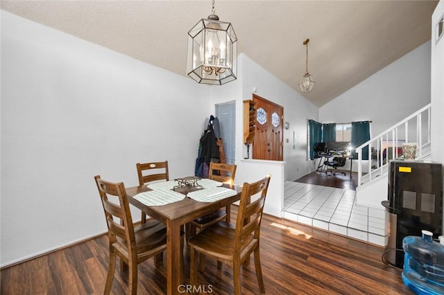 dining room with dark wood-type flooring, high vaulted ceiling, and an inviting chandelier