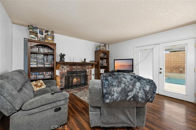 living room with dark hardwood / wood-style flooring, a wealth of natural light, a fireplace, and a textured ceiling