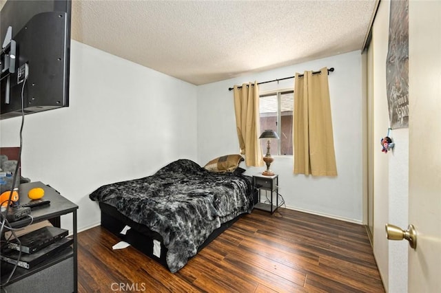 bedroom with dark wood-type flooring and a textured ceiling