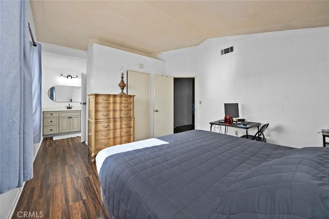 bedroom featuring dark wood-type flooring, vaulted ceiling, and ensuite bath