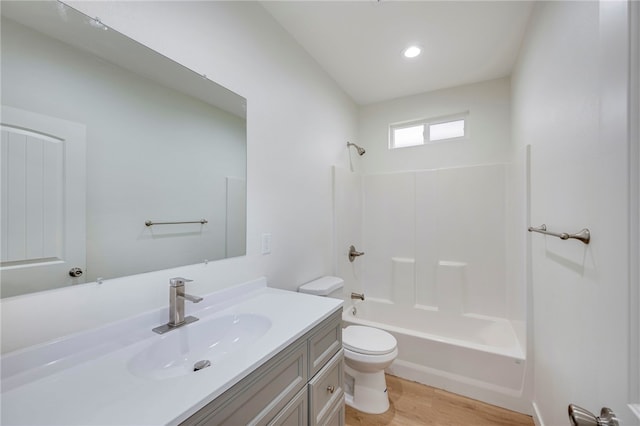 full bathroom featuring vanity, hardwood / wood-style flooring, toilet, and washtub / shower combination