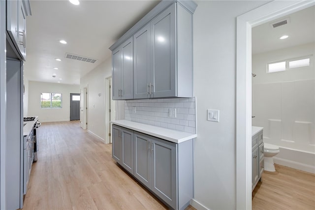 kitchen featuring gray cabinetry, backsplash, and light wood-type flooring