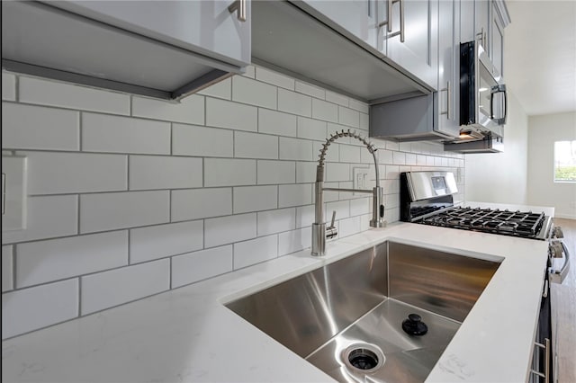 kitchen with gray cabinetry, backsplash, sink, and appliances with stainless steel finishes