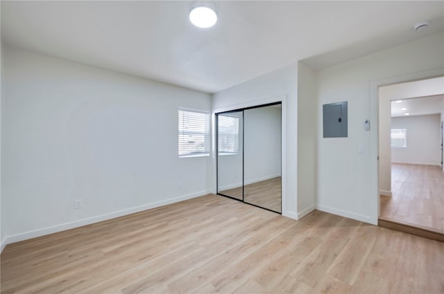 unfurnished bedroom with light hardwood / wood-style flooring, electric panel, and a closet