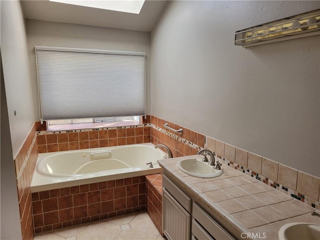 bathroom with a relaxing tiled tub, vanity, and tile patterned flooring