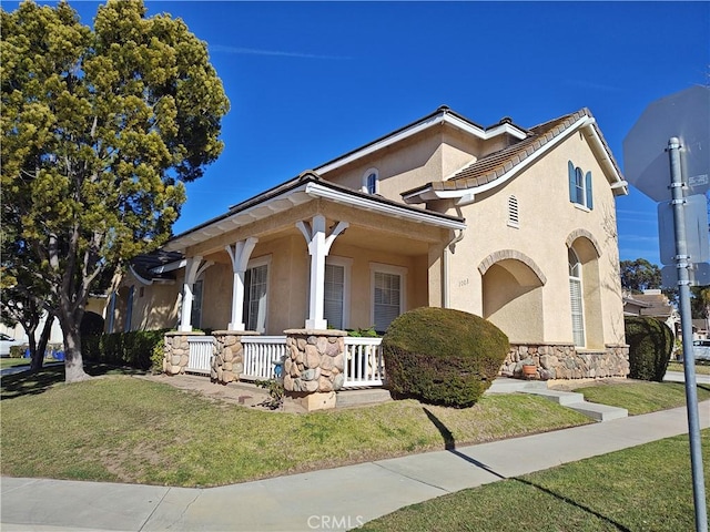 mediterranean / spanish-style house featuring a front lawn and covered porch