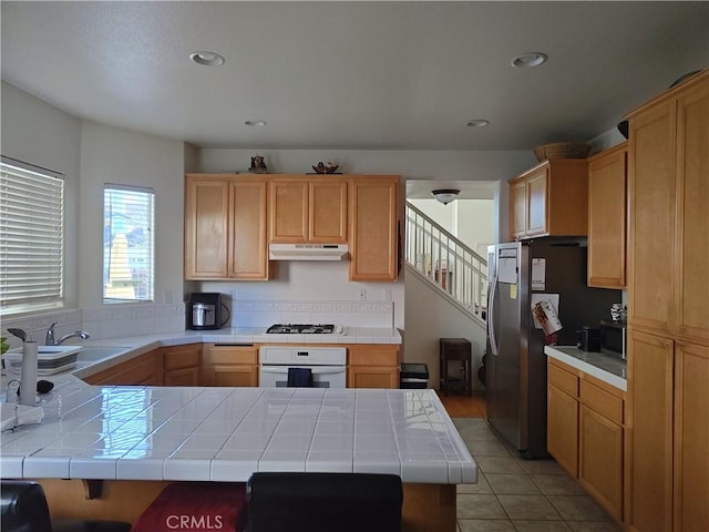 kitchen with sink, tile countertops, white appliances, and kitchen peninsula