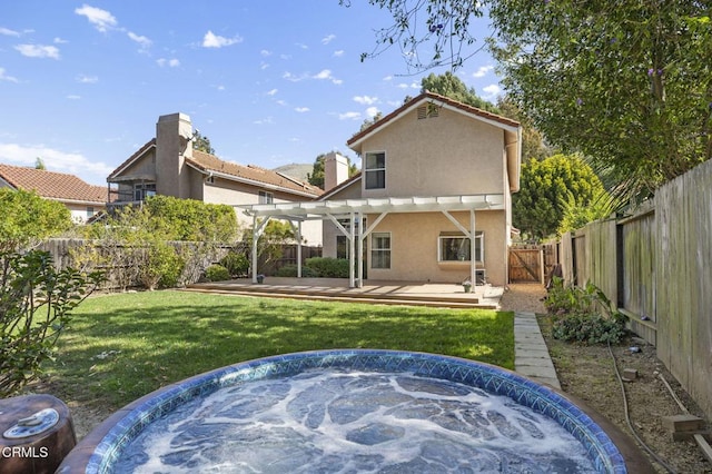 rear view of property featuring stucco siding, a lawn, a pergola, a fenced backyard, and a jacuzzi