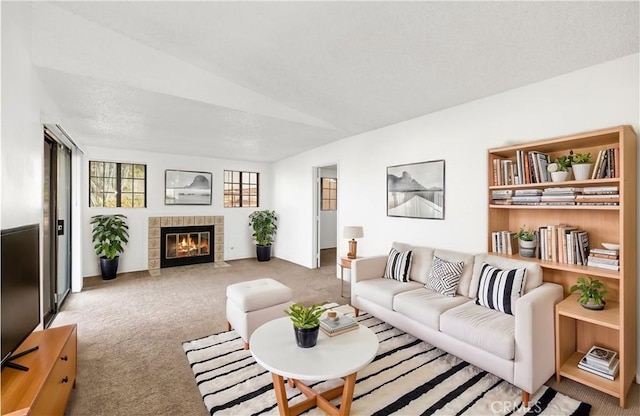 carpeted living room with a tile fireplace and vaulted ceiling