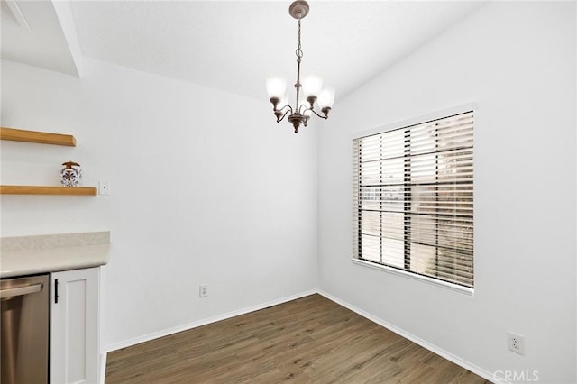 unfurnished dining area featuring lofted ceiling, dark hardwood / wood-style floors, and a chandelier