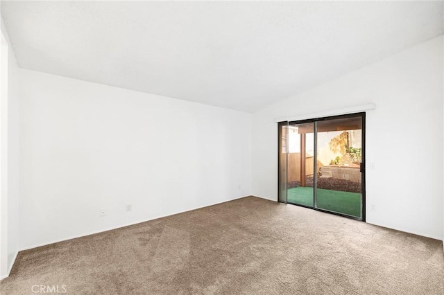 carpeted spare room featuring vaulted ceiling