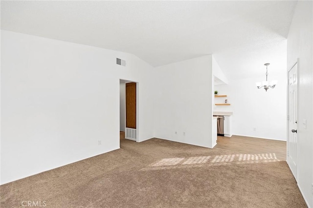 carpeted spare room with lofted ceiling and an inviting chandelier