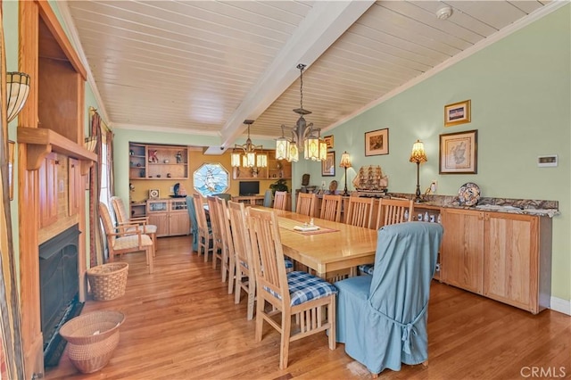 dining space with beamed ceiling, ornamental molding, and light hardwood / wood-style floors