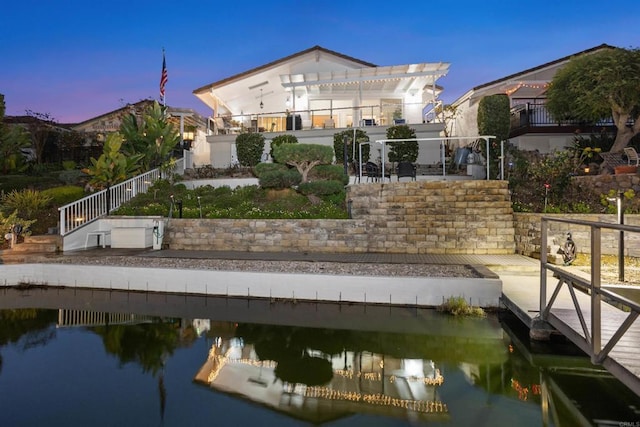 rear view of property featuring a water view and a pergola