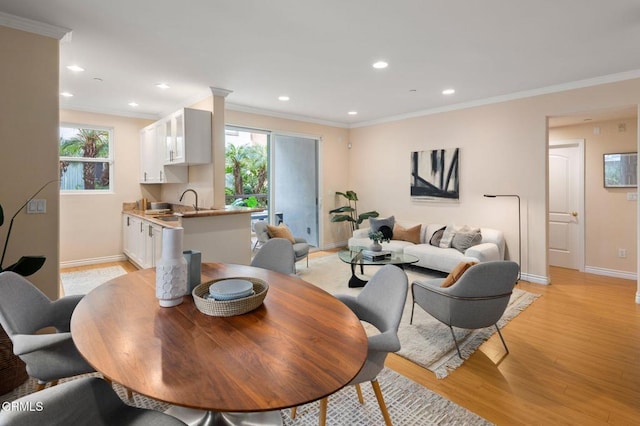 dining space featuring crown molding, sink, and light wood-type flooring