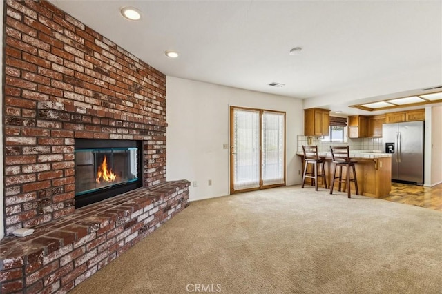 living room with a brick fireplace and light colored carpet