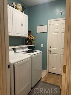 laundry area with cabinets, hardwood / wood-style floors, and washing machine and clothes dryer