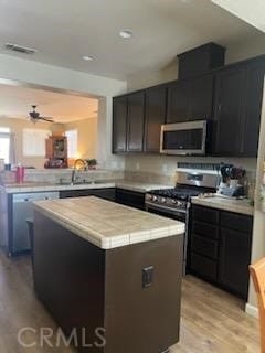 kitchen with sink, a center island, dark brown cabinets, light hardwood / wood-style flooring, and stainless steel appliances