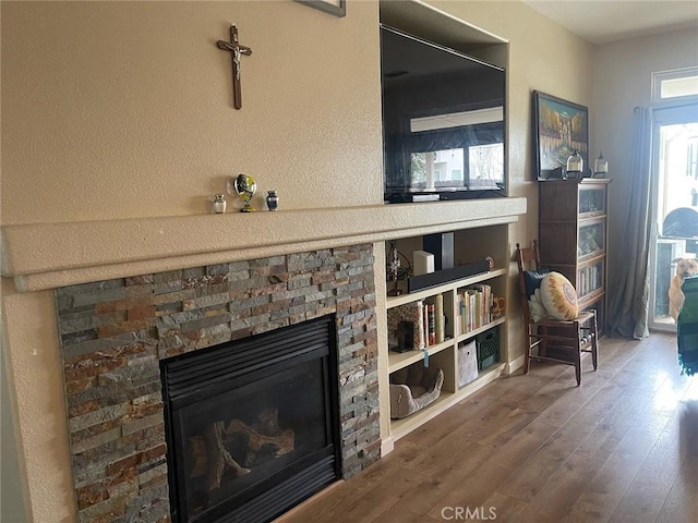 living room featuring wood-type flooring and a stone fireplace