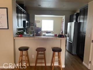 kitchen featuring tile counters, a kitchen breakfast bar, kitchen peninsula, and stainless steel appliances