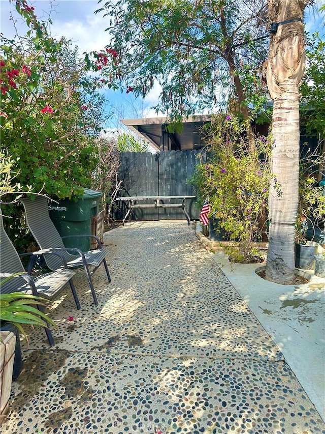 view of gate with fence and a patio