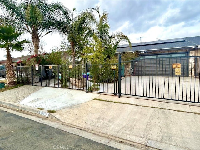 view of gate with solar panels and a fenced front yard