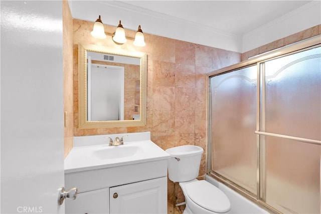 full bathroom with toilet, combined bath / shower with glass door, crown molding, tile walls, and vanity