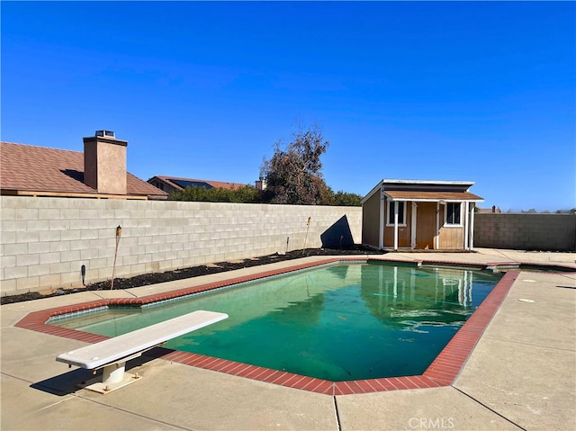 view of pool featuring an outdoor structure, a diving board, and a patio area