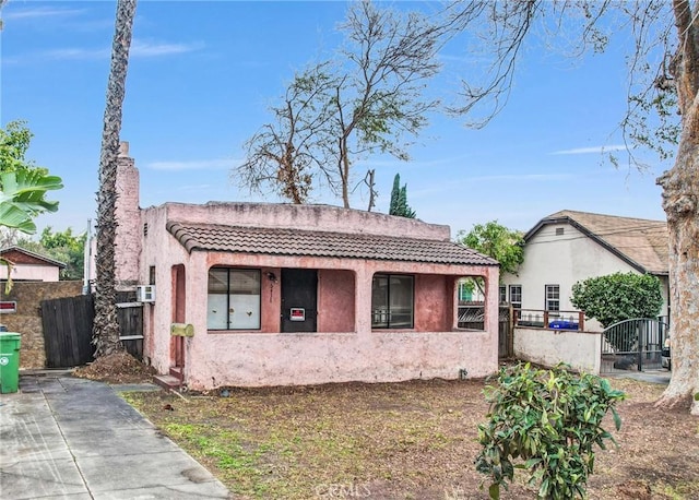 view of front of house with a fenced front yard, a tile roof, a gate, and stucco siding