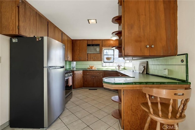 kitchen with stainless steel appliances, decorative backsplash, a kitchen bar, and kitchen peninsula