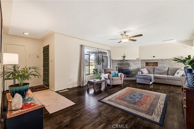 living room with dark wood-type flooring, ceiling fan, and a brick fireplace