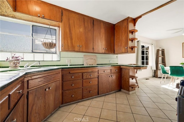 kitchen with backsplash, light tile patterned floors, sink, and ceiling fan