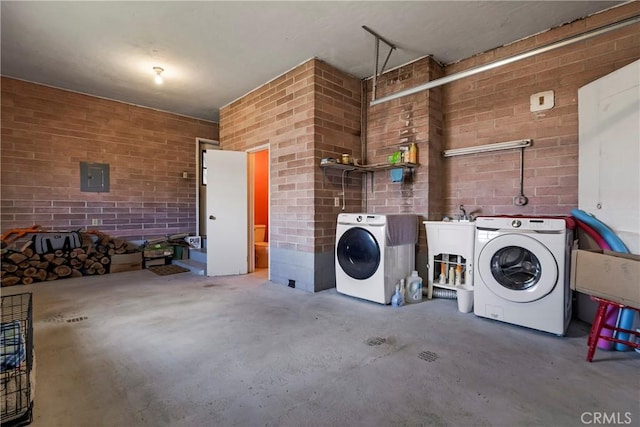 interior space featuring brick wall, electric panel, and washer and clothes dryer