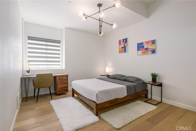 bedroom featuring an inviting chandelier and light hardwood / wood-style floors