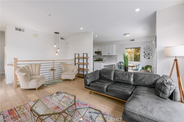 living room featuring sink and light hardwood / wood-style flooring