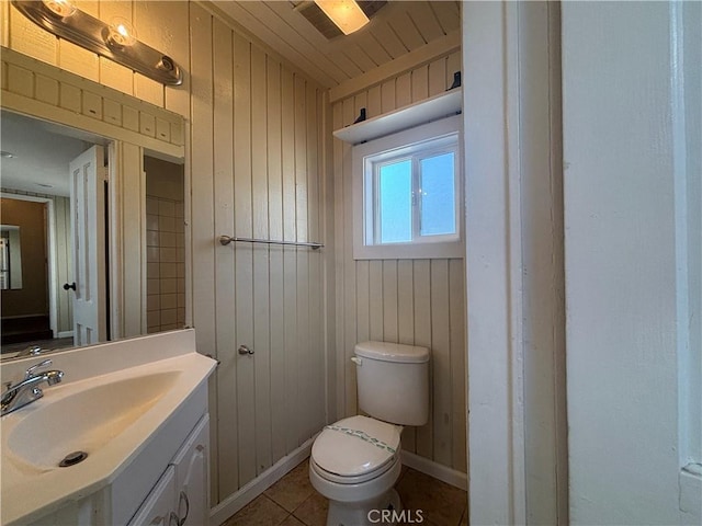 bathroom featuring vanity, tile patterned flooring, toilet, and wood walls