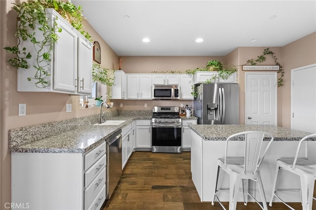 kitchen featuring stainless steel appliances, a breakfast bar, sink, and white cabinets