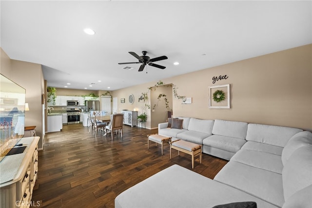 living room with dark wood-type flooring, ceiling fan, and sink