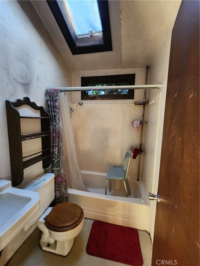 bathroom featuring a skylight, shower / bath combination with curtain, and toilet