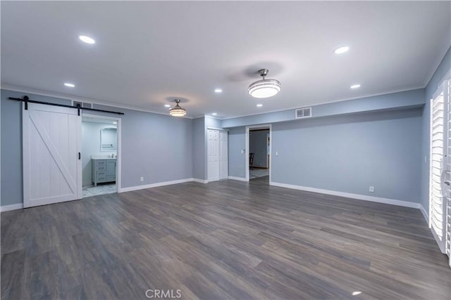 interior space with ornamental molding, a barn door, and dark hardwood / wood-style flooring