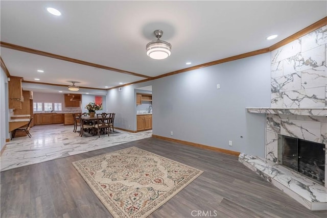 living room featuring crown molding, hardwood / wood-style flooring, a premium fireplace, and ceiling fan