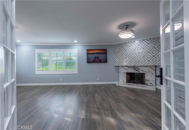 unfurnished living room with a premium fireplace, dark wood-type flooring, and ornamental molding