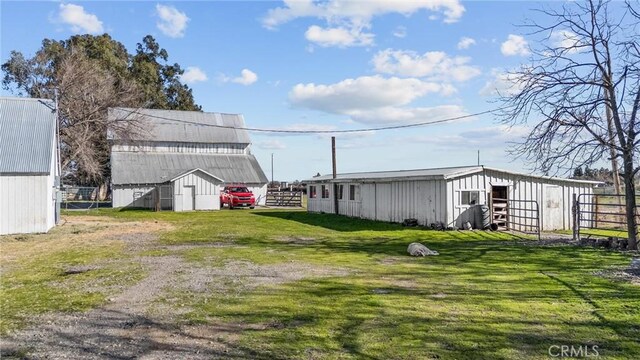 view of yard featuring an outbuilding, driveway, an outdoor structure, and fence