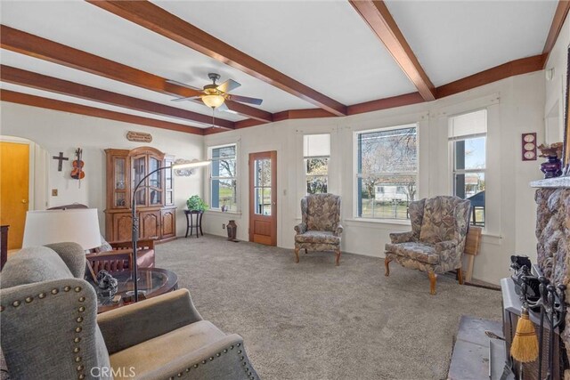 living area featuring arched walkways, beam ceiling, light carpet, and a wealth of natural light