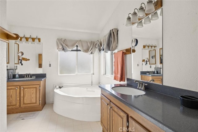 full bath featuring lofted ceiling, a garden tub, two vanities, and a sink