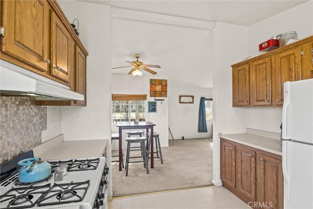 kitchen featuring light countertops, white appliances, brown cabinetry, and a healthy amount of sunlight