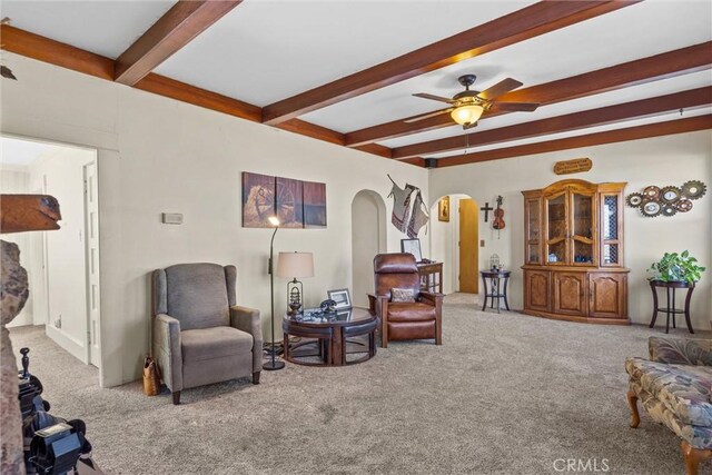 living room with carpet floors, ceiling fan, arched walkways, and beamed ceiling