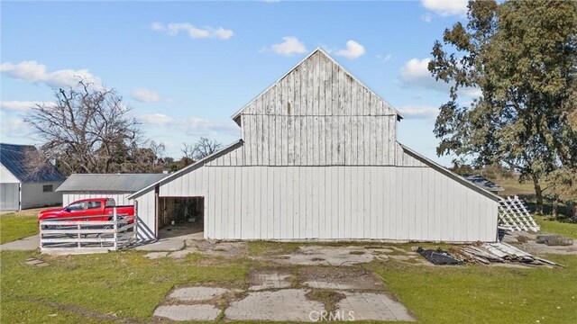 view of side of home featuring a garage, a yard, an outdoor structure, and a barn