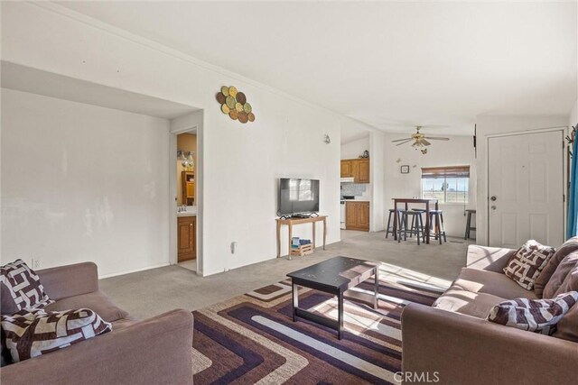 living area featuring a ceiling fan, lofted ceiling, and light colored carpet