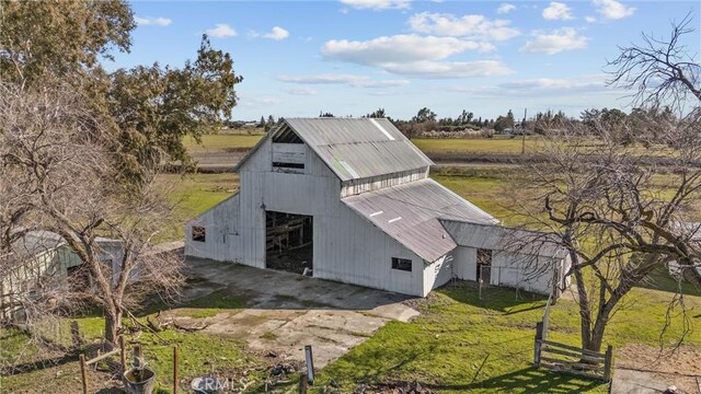 view of barn with a yard, fence, and a rural view